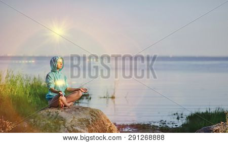 Beautiful Peaceful Woman Sits In A Pose Of A Half Lotus Practicing Yoga Meditation, Blue Summer Sky,