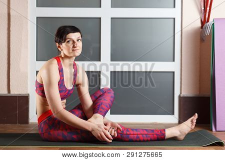 Young Sporty Woman Practicing Yoga, Doing Mahamudra Stretching Position In A Fitnes Club