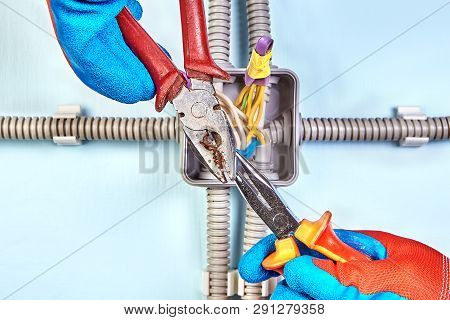 Electrician In Protective Gloves Twists Ends Of Wires Together With Needle-nose Pliers.