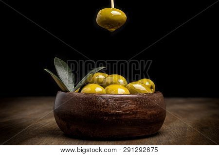 Green Olives And Leaves On A Wooden Table