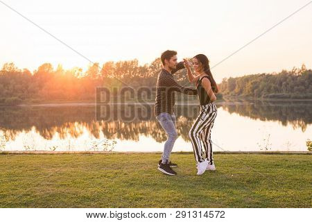 Romantic, Social Dance, People Concept - Young Couple Dancing Bachata Near The Lake In Sunny Day