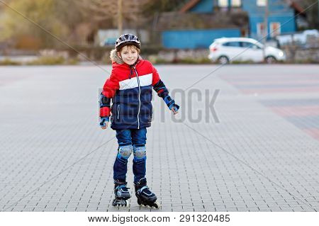 Cute School Kid Boy Skating With Rollers In The City. Happy Healthy Child In Protection Safety Cloth
