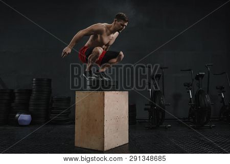 Box Jump Exercise. Athlete Jumping Onto The Box At The Gym. Man Doing A Box Squat Legs Training. Cop