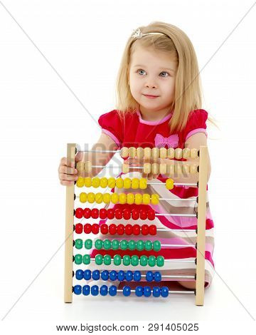 Cute Little Girl Is Playing With Wooden Abacus At Home. An Intelligent Child Learns To Count. She En