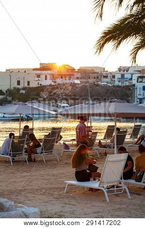 Lampedusa, Italy - August, 01: People Sitting In Deck Chairs In The Beach Bar At The Sunset On Augus