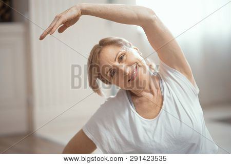 An Adult Woman Of About 50 Enjoys Yoga. She Conducts Classes At Home. Yoga Improves Her Mood. Close 