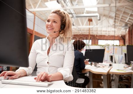 Female Customer Services Agent Working At Desk In Call Center