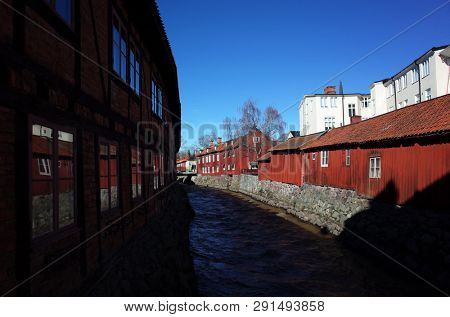 Vasteras, Sweden - 22 March, 2019: Swedish style red houses and Black river in early spring, Idyllic nordic cityscape