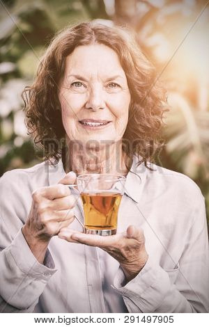 Portrait of smiling mature woman drinking herbal tea, Close-up
