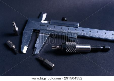 Vintage Steel Caliper With Modern Tool Bits And Bitholder On Dark Background. Caliper And Bitholder 