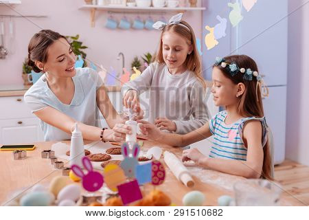 Positive Delighted Girls Helping Their Mother In Baking
