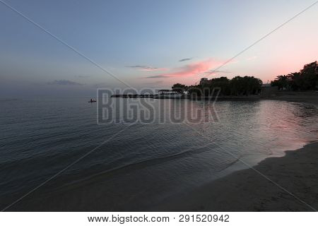 Pink And Blue Sunset On The Beach In Creta, Greece. Beach With Blacks Rocks And Waves At Dusk
