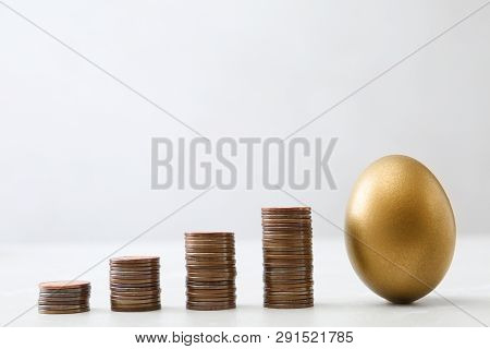 Gold Egg And Stacks Of Coins On Table