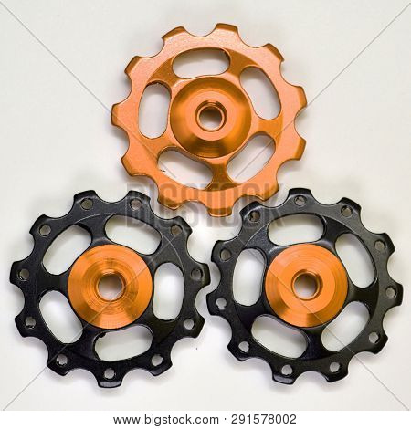 Three Color Rollers, Black, Golden Gears For Bicycle Rear Derailleur On A White Background