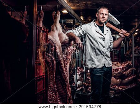 The Butcher In A White Work Shirt Holding Ax While Standing In A Refrigerated Warehouse In The Midst