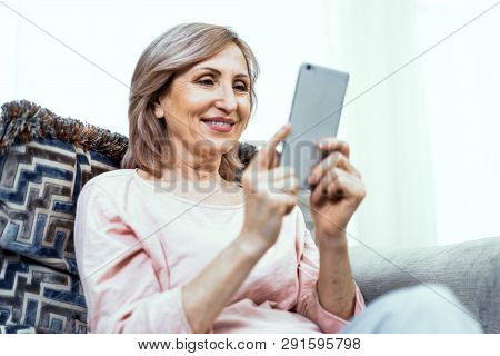 Woman Of European Appearance At Home On The Couch With A Phone In Her Hands. In Appearance Woman Are