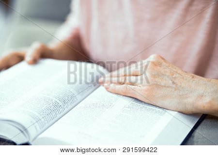 Middle Aged Woman Sitting On Sofa And Reading Bible. Being Religious. Religion Concept. Selective Fo