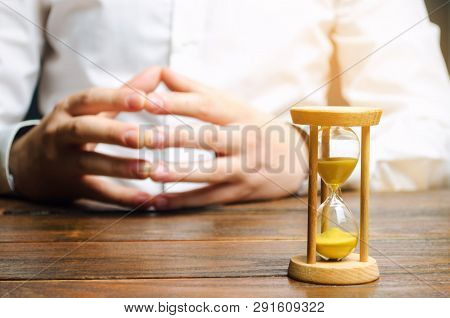 An Hourglass And Businessman Holds His Hands In The Lock. Job Interview Concept. Business Planning. 
