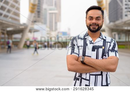 Happy Young Bearded Indian Man With Arms Crossed In The City Outdoors
