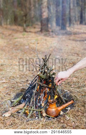 At The Stake In The Spring Forest, A Clay Turkish Coffee Pot Is Heated Against The Grass. In The Fra