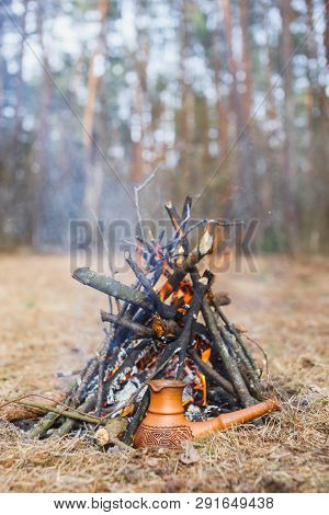 At The Stake In The Spring Forest, A Clay Turkish Coffee Pot Is Heated Against The Grass.