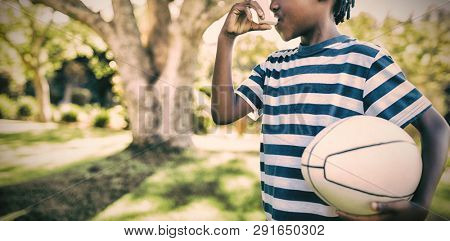 Boy using asthma inhaler in the park on a sunny day