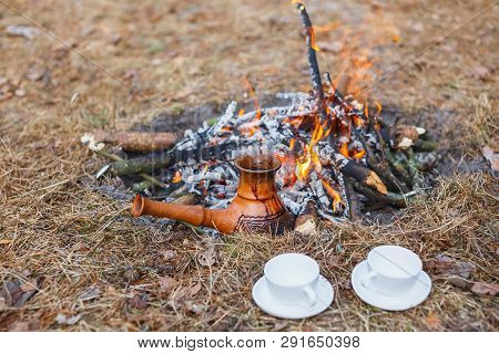 At The Stake In The Spring Forest, A Clay Turkish Coffee Pot Is Heated Against The Grass.