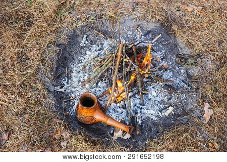 At The Stake In The Spring Forest, A Clay Turkish Coffee Pot Is Heated Against The Grass.