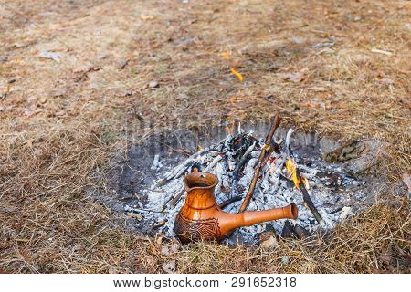 At The Stake In The Spring Forest, A Clay Turkish Coffee Pot Is Heated Against The Grass.