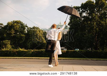 Young Couple Jump Up With Black Upbrella. Lovely Cuople Have Fun