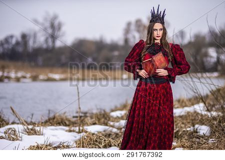 Art Photography Ideas. Mysterious Fairy Princess In Red Dress And Black Crown Reading Old Book. Posi