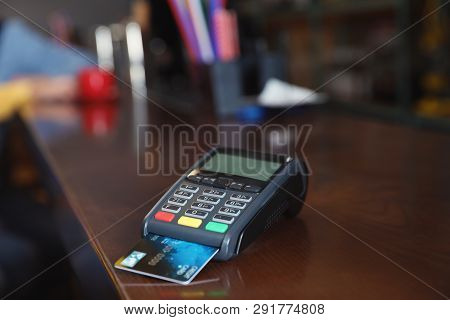 Credit Card Machine For Non Cash Payment On Wooden Counter In Cafe. Space For Text