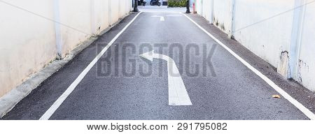 White Arrow Traffic Sign Indicates Minor Road To Turn Left To Major Road And White Footpath Lines On