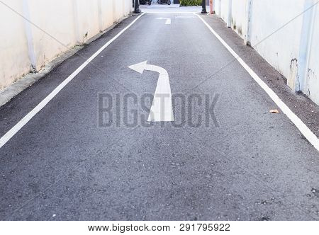 White Arrow Traffic Sign Indicates Minor Road To Turn Left To Major Road And White Footpath Lines On