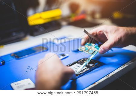 Man fixing broken phone. Professional service, electronical devices reparation.