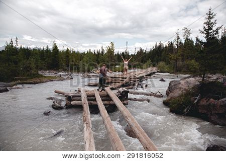 Old, Broken, Wooden Bridge Over The River In The Altai Mountains. Extreme Crossing The River