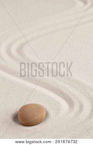 Spa wellness for inner life and spiritual health. Zen meditation stone for relaxation. Concept for purity balance and harmony. Background with raked sand and open copy space.