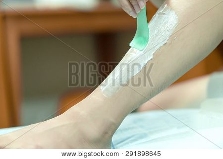 Woman Epilating Leg With Depilation Cream And Spatula. Scrubs Hair Removal Cream