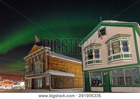 Dawson City, Yukon, Canada, March 12, 2019 : Northern Lights Above The Old Houses Of The Gold Rush C
