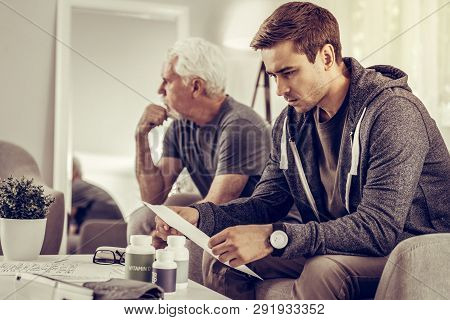 Concerned Son Considering The Medical Assessment Of His Silver-haired Father