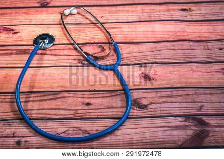 Blue Stethoscope With Earpiece On Grainy Wooden Table