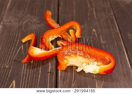 Group Of Four Slices Of Bulgarian Red Bell Pepper On Brown Wood