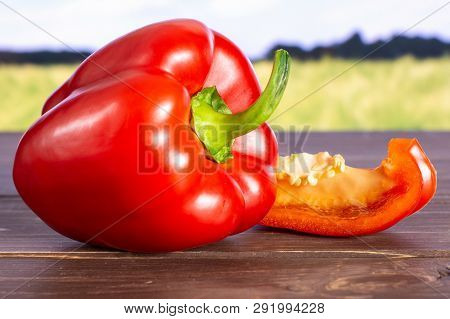 Group Of One Whole One Slice Of Bulgarian Red Bell Pepper With Green Wheat Field In Background