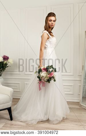Beautiful Tender Young Bride In A Luxurious Wedding Dress With Flower Bouquet. Full Lenth