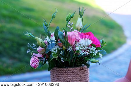 Beautiful Delicate Bouquet Of Flowers In A Wicker Box On A Grassy Background . Present