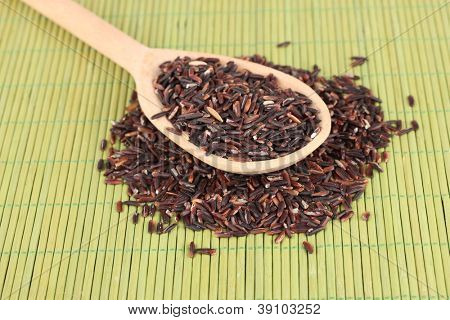 arroz preto com colher de pau, na esteira de bambu