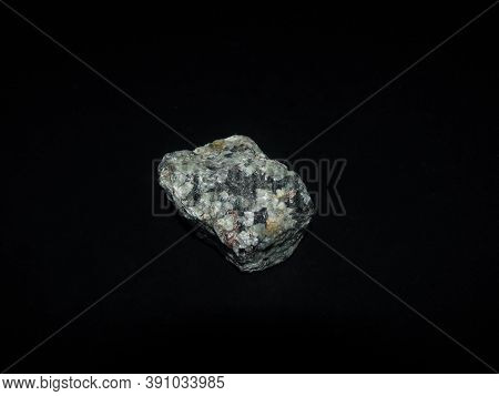 A Sample Of The Urtite Rock Is Gray-green On A Black Background
