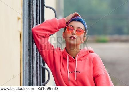 Portrait Of A Young Girl With Short Colorful Hair And Nose Piercing Satanding Near The Wall With Woo