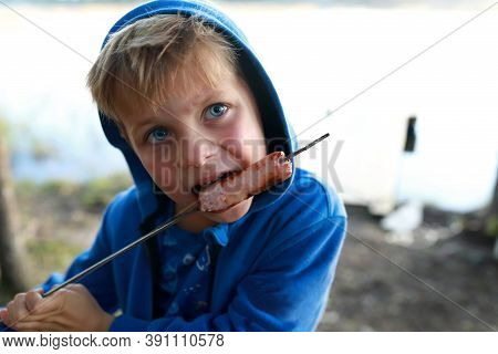 Child Eating Sausage On Skewer By Lake