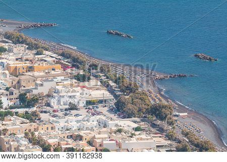 Kamari, Santorini Island, Greece- 19 September 2020: Black, Volcanic Beach Wit Chairs Lawn In Kamari